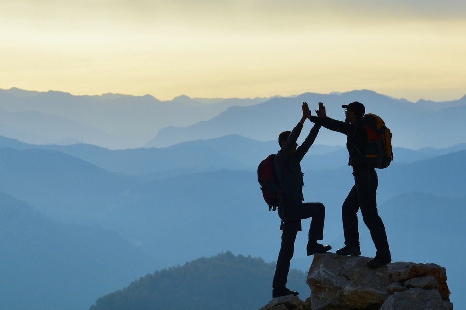Zwei Bergsteiger auf einem Gipfel als Symbol für eine erfolgreiche, partnerschaftlich begleitete und nachhaltig umgesetzte SAP S/4HANA Transformation.