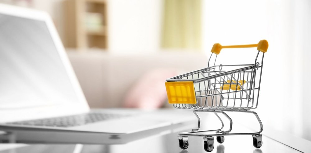 Einkaufswagen vor einem Laptop als Symbol für den digitalen Source-to-Pay-Einkaufsprozess in SAP S/4HANA